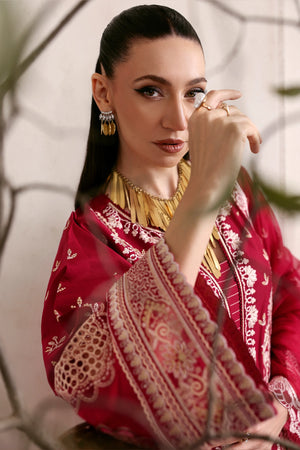 Woman wearing a red and gold traditional outfit with jewelry, sitting outdoors.