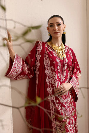 Woman wearing a red embroidered traditional outfit with gold jewelry against a neutral background