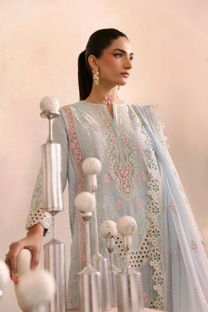 Woman in a light blue embroidered traditional outfit with decorative elements.
