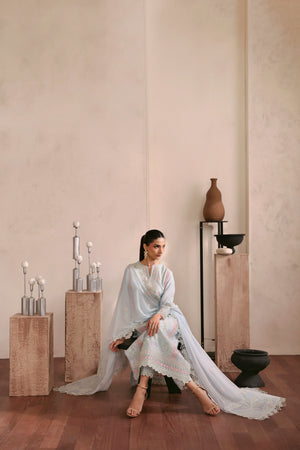 Woman in a white dress sitting in a minimalistic room with neutral colors.