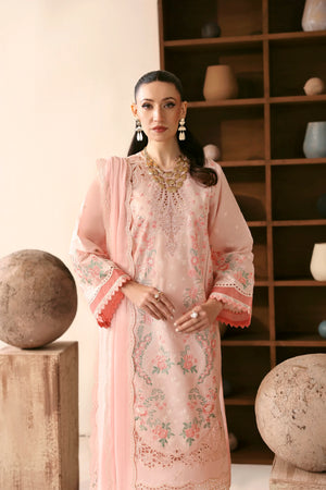 Woman in a pink traditional outfit with floral patterns standing in a room with shelves and decorative items.