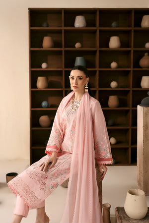 Woman in a pink traditional outfit standing in front of a bookshelf with decorative items.