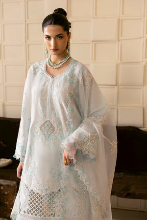 Woman wearing a light blue embroidered dress with a white background