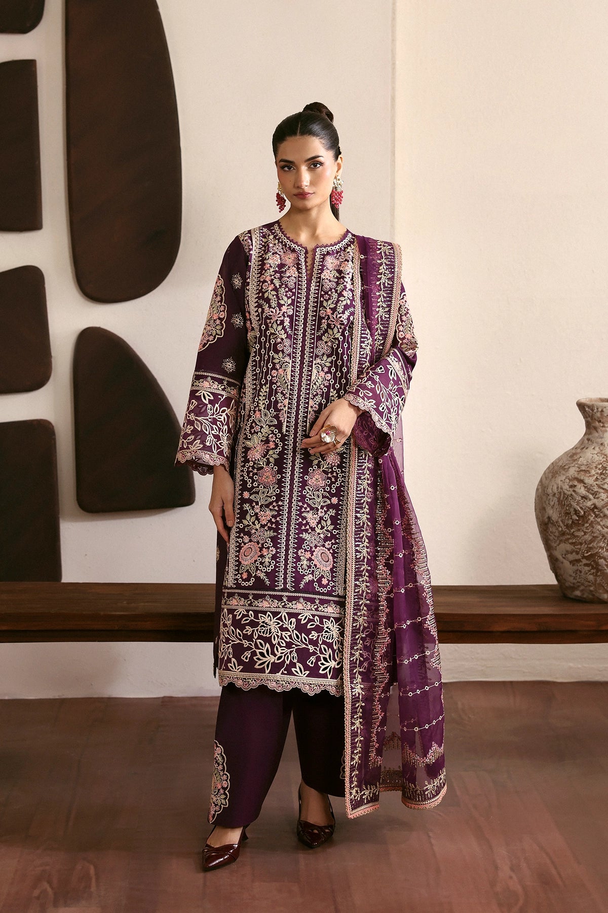 Woman in a traditional outfit with floral patterns standing indoors.
