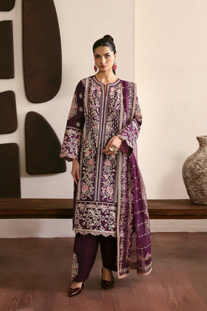 Woman in a traditional outfit with floral patterns standing indoors.