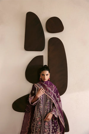 Woman in a patterned outfit standing against a wall with abstract black shapes.