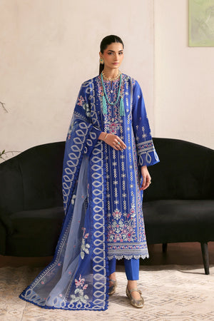 Woman wearing a blue embroidered traditional outfit in a living room setting.