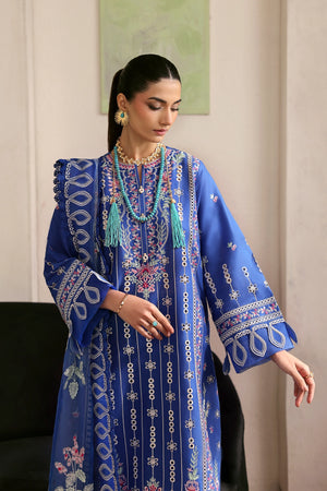 Woman wearing a blue embroidered dress with tassels indoors.