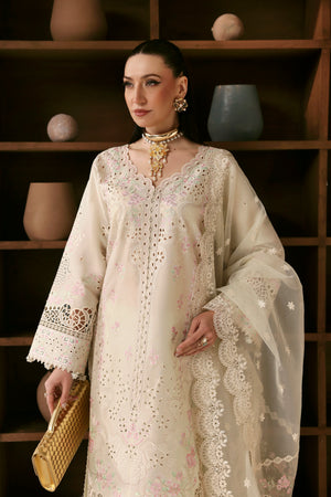 Woman wearing a cream embroidered dress against a wooden shelf background