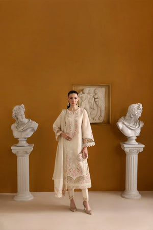 Woman in a cream embroidered outfit standing between classical busts against an orange wall.
