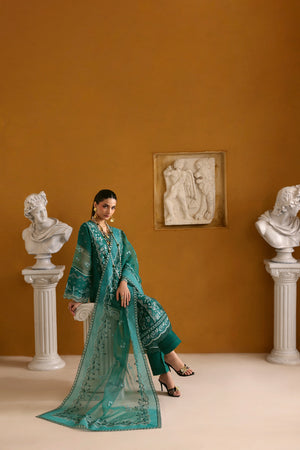 Woman in a teal traditional outfit standing in an elegant room with classical sculptures.